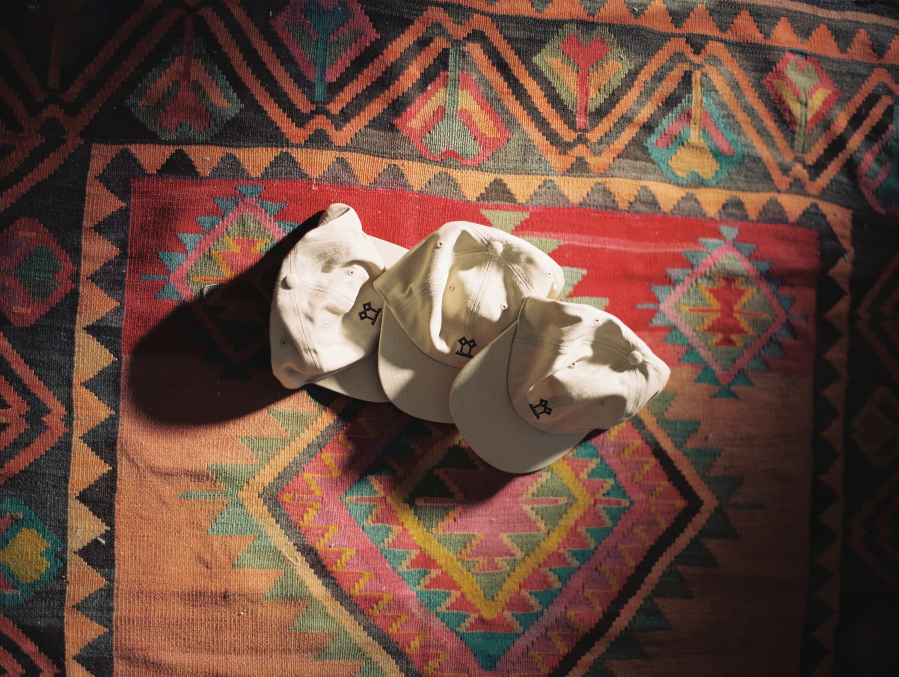 BERQ caps photographed on a patterned rug